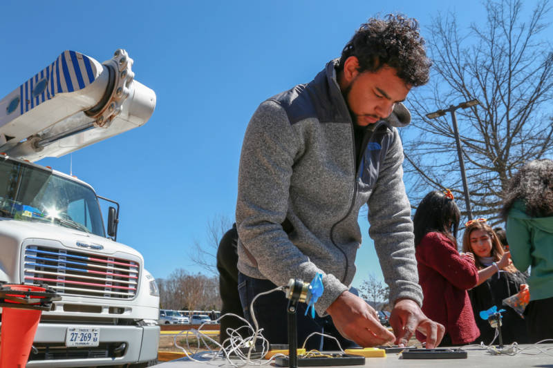 Student working on a solar installation next to a bucket truck