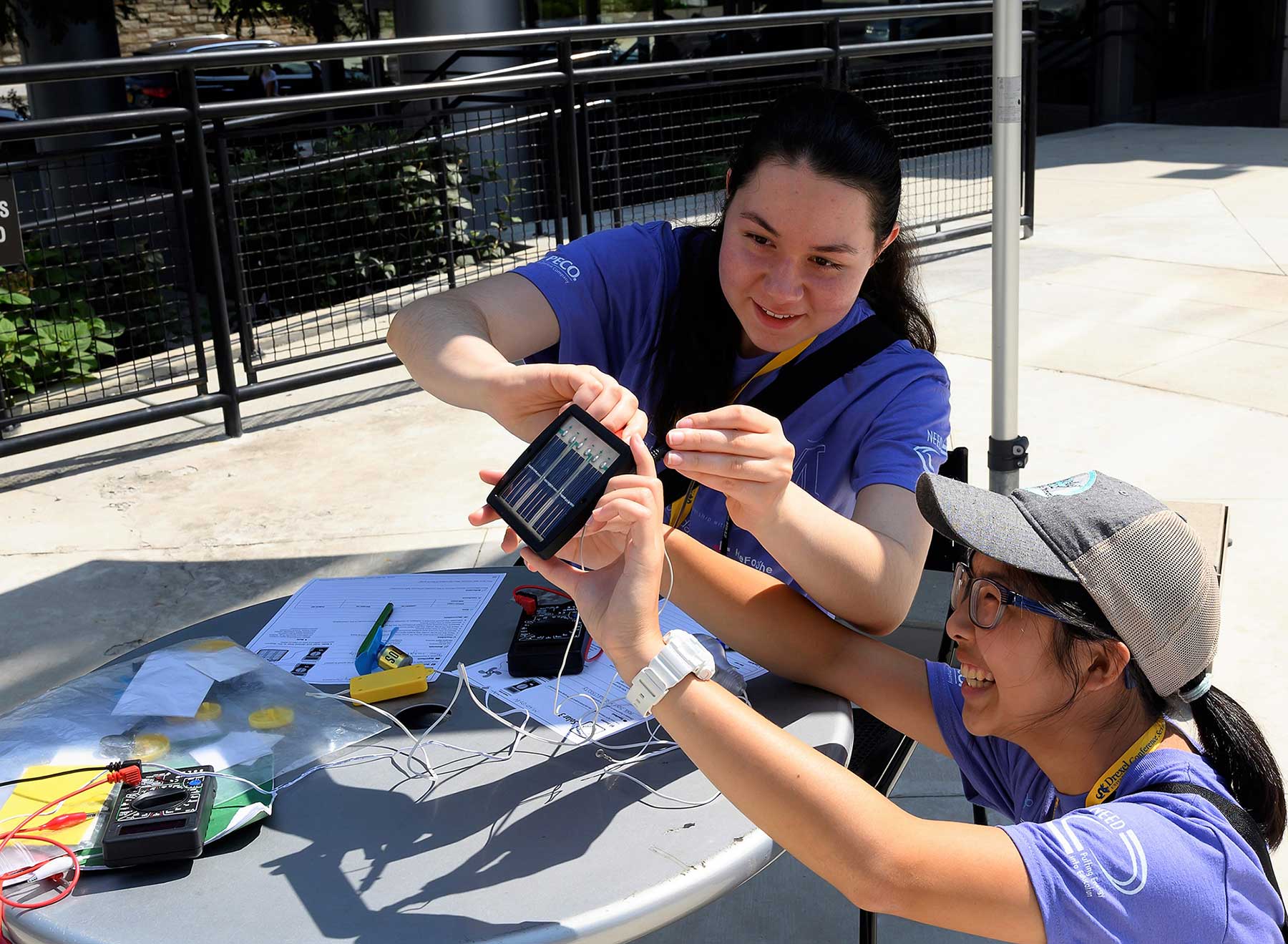 Students using a portable solar panel to generate electricity