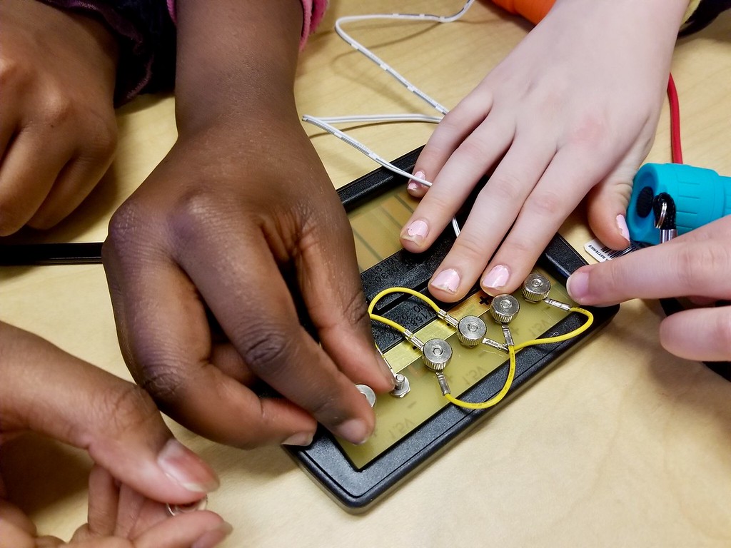 Children connecting wires to a breaker board as part of an experiment
