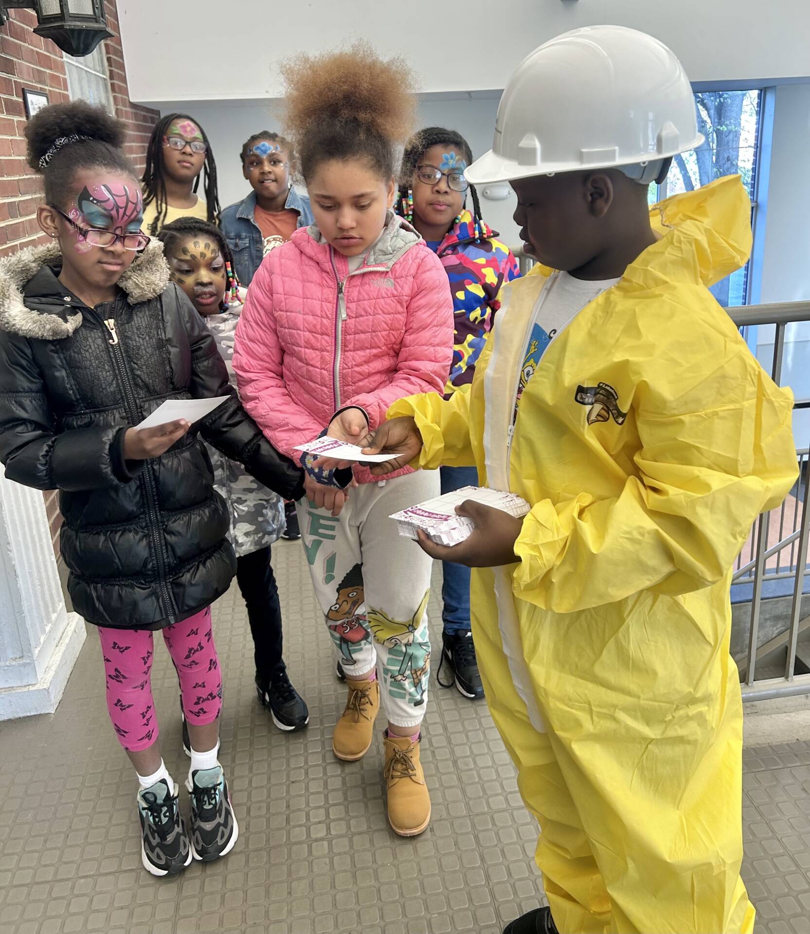 Man in a hazmat suit showing students around a power plant