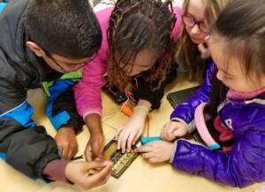 Three students operating a wiring acoustic board